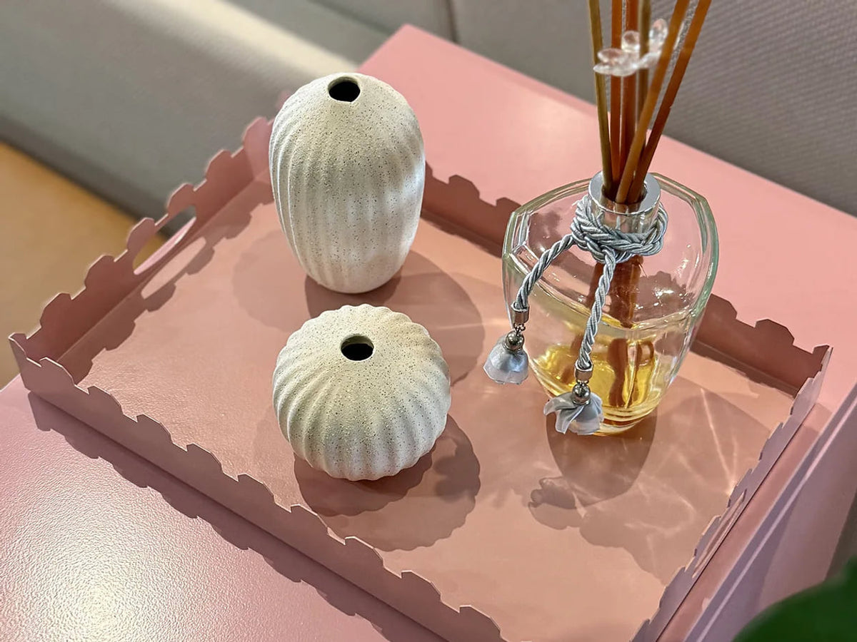 Bandeja Castle rosa com vasos e objetos decorativos sobre uma superfície rosa